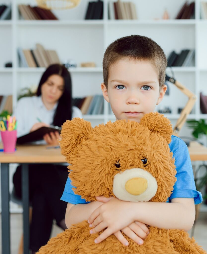 Young female psychologist working with little boy in office